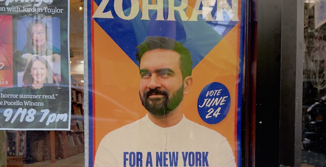 A Mamdani poster in a window of a store.